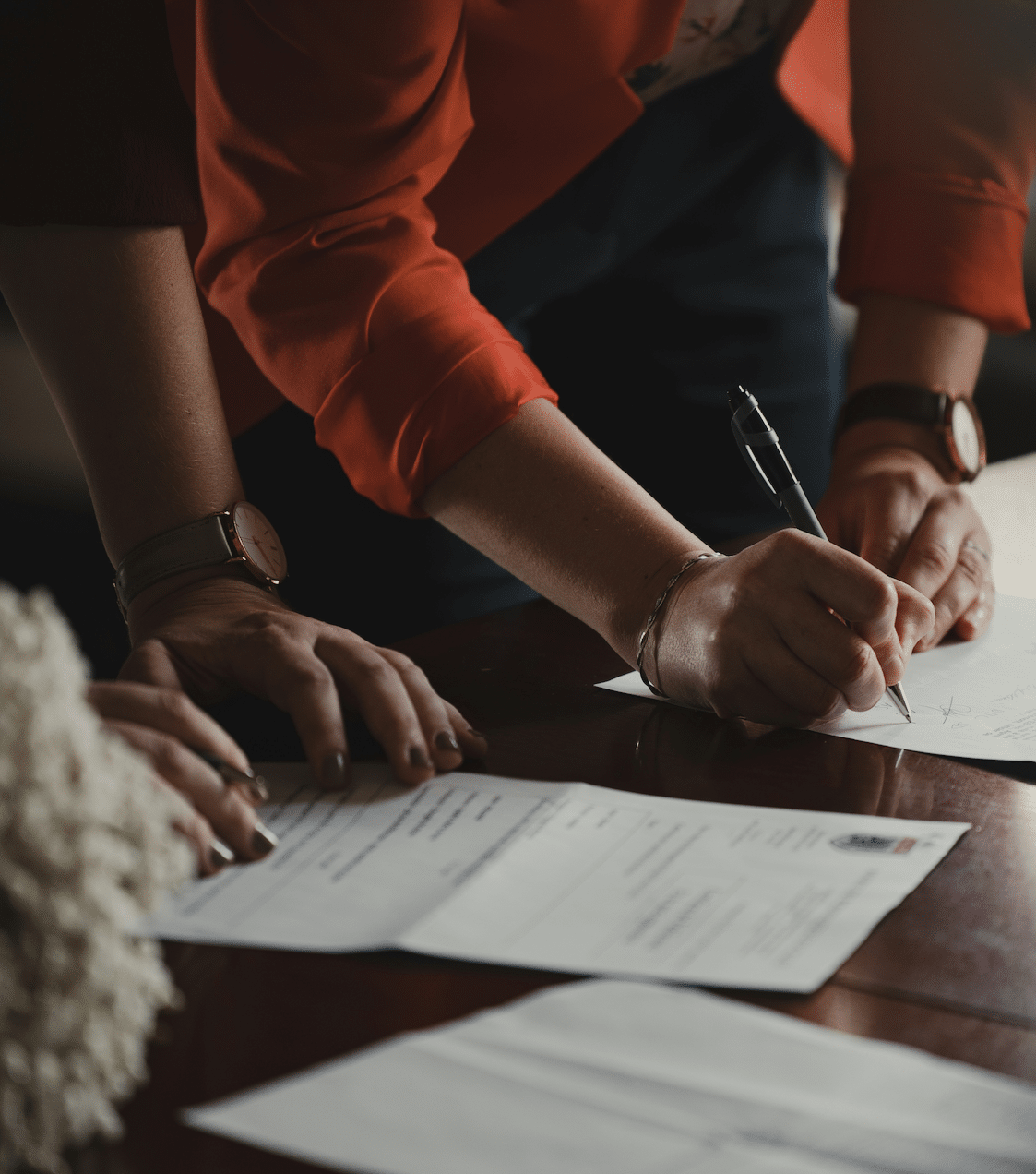 People reviewing and signing papers at a desk.