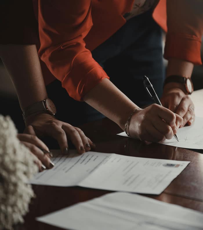 People reviewing and signing papers at a desk.